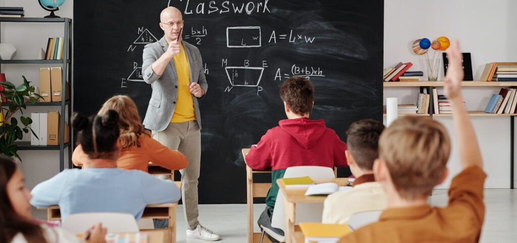 male bald teacher calling on student in math class