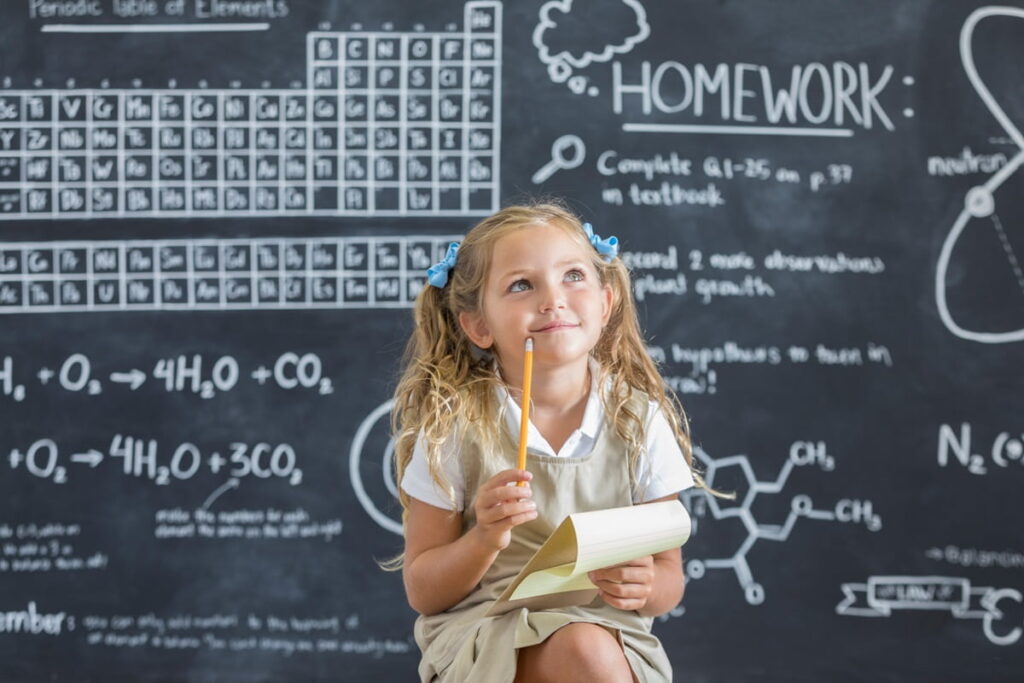 Girl looking up thinking in front of chalk board