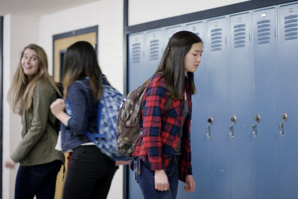 Sad Asian teenage girl walking to locker at school