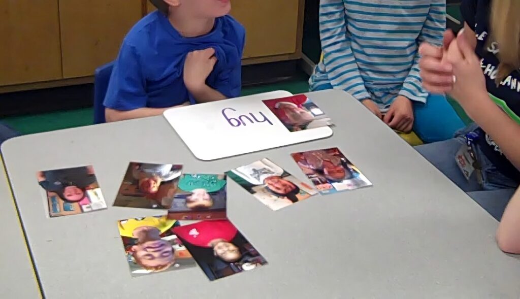 student practices reading 'hug' with teacher and pictures of his classmates.