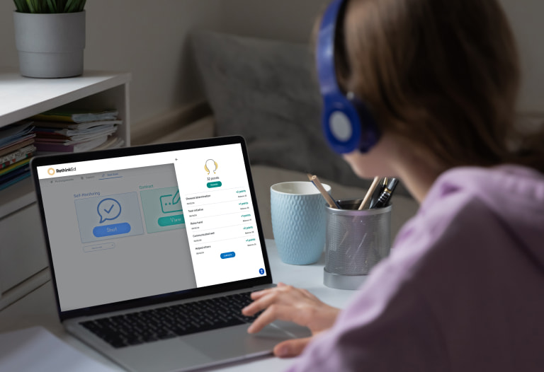 young student wearing headphones using RethinkEd Behavior Suite at home on laptop