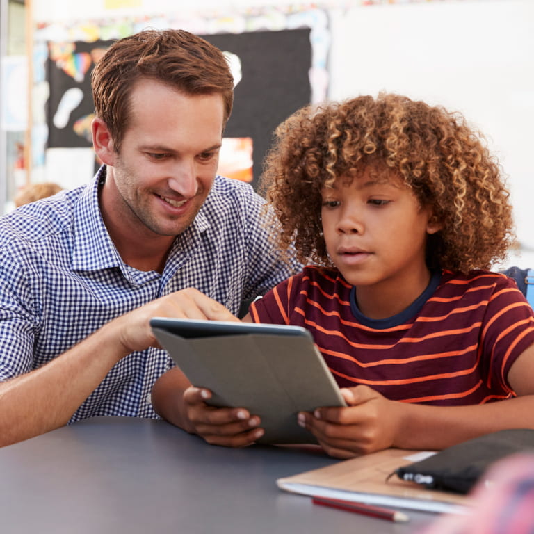 Male Caucasian teacher and male grade school student using tablet